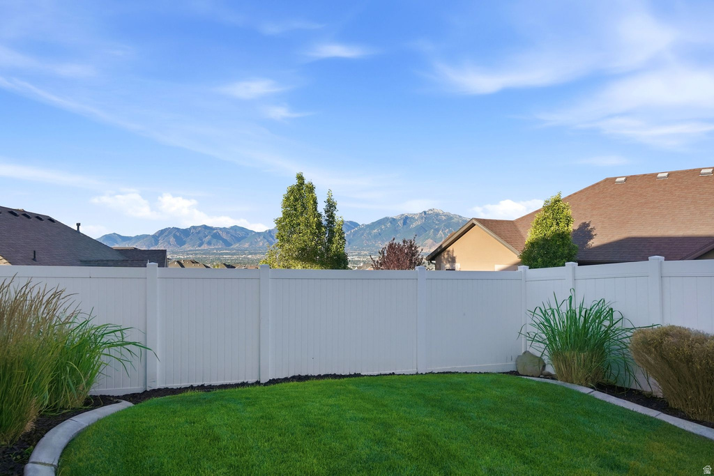 Expansive backyard featuring a lush lawn, white privacy fencing, and a concrete curbing defining planting beds