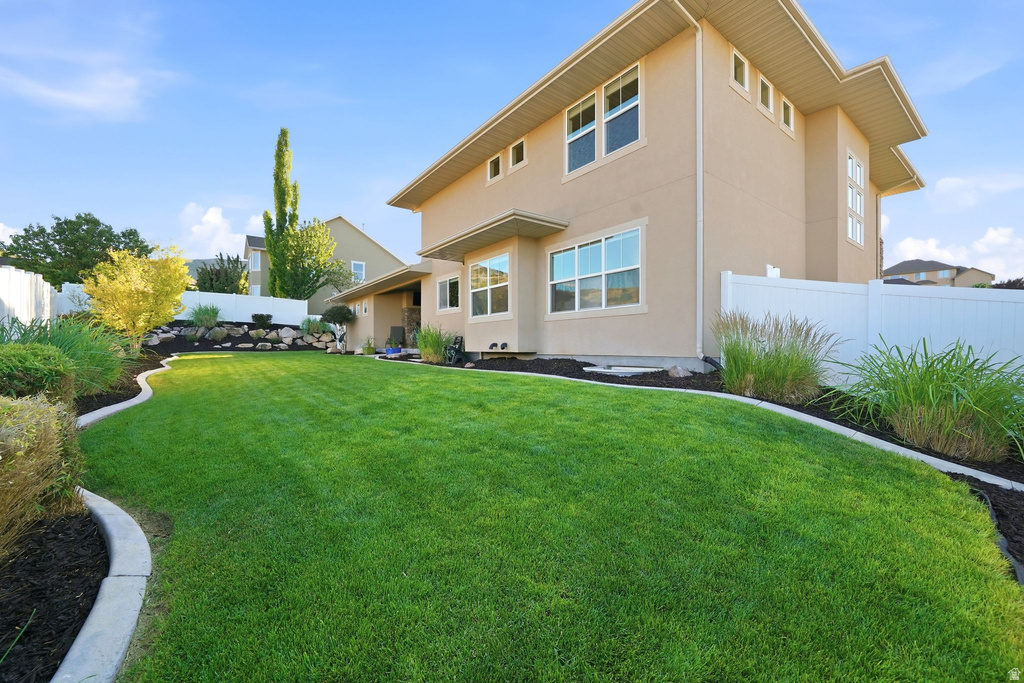 Expansive backyard featuring a manicured lawn, established landscaping, and a tan stucco exterior