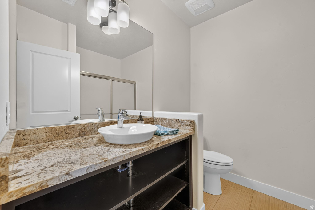 Bathroom vanity featuring a vessel sink, a granite-finish countertop, and open shelving