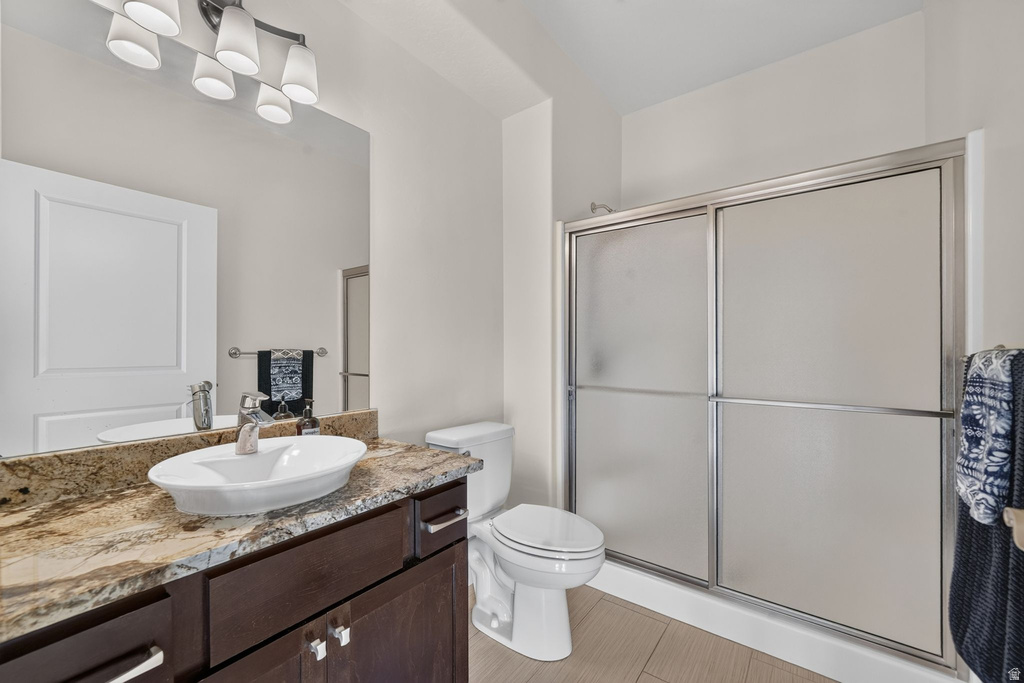 Bathroom featuring a dark wood-finish vanity with a vessel sink, a multi-tone stone countertop, and a vanity mirror