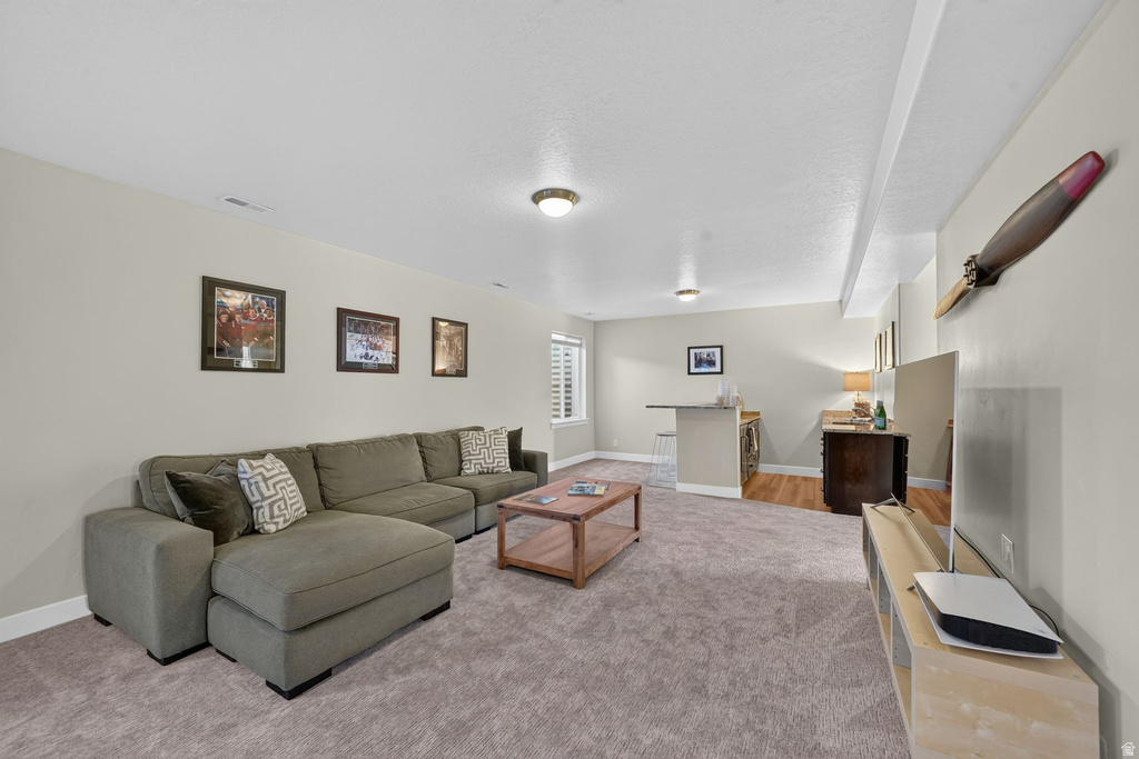 Spacious room featuring neutral carpeting, recessed lighting, and a built-in wet bar with a countertop