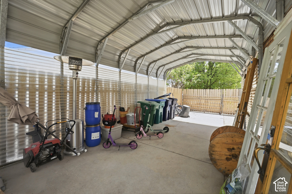 Covered outdoor structure with a metal roof and framework, concrete slab flooring, and a corrugated metal partition