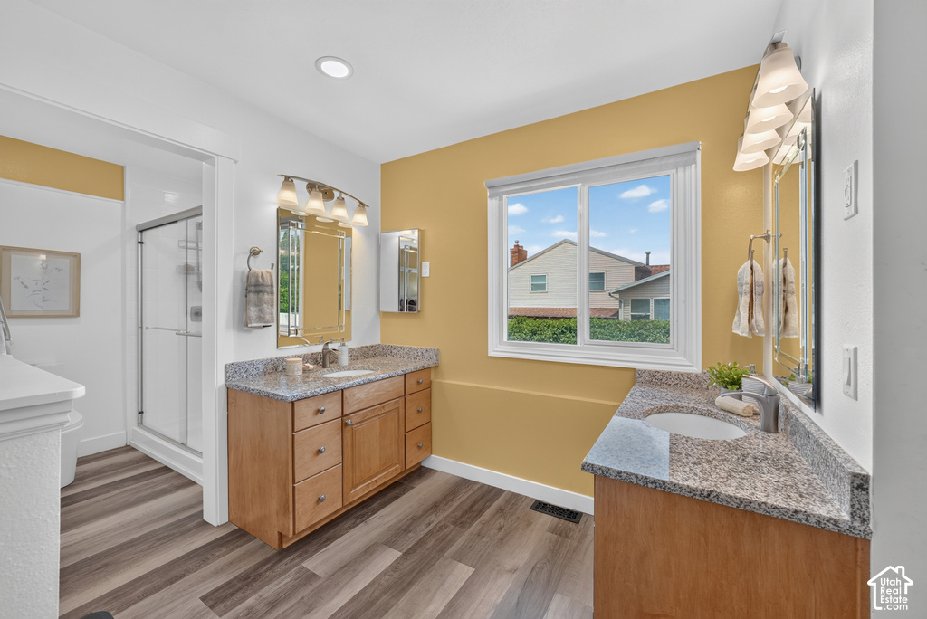 Bathroom featuring a double vanity with wood-finish cabinetry, speckled countertops, and undermount sinks