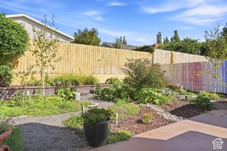 Expansive backyard featuring a gravel pathway, raised brick planters, and mature landscaping