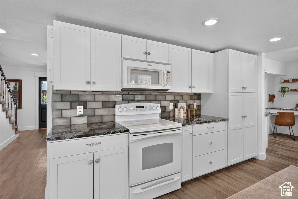 Kitchen featuring white cabinetry, dark stone countertops, and a gray subway tile backsplash