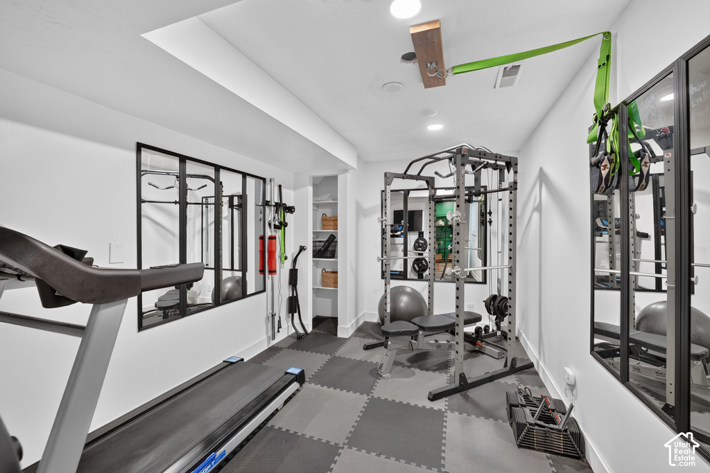 Dedicated exercise room featuring checkerboard pattern floor tiles and bright recessed lighting