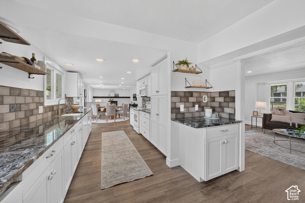 Modern kitchen with white cabinetry, wood-finish flooring, and dark patterned countertops