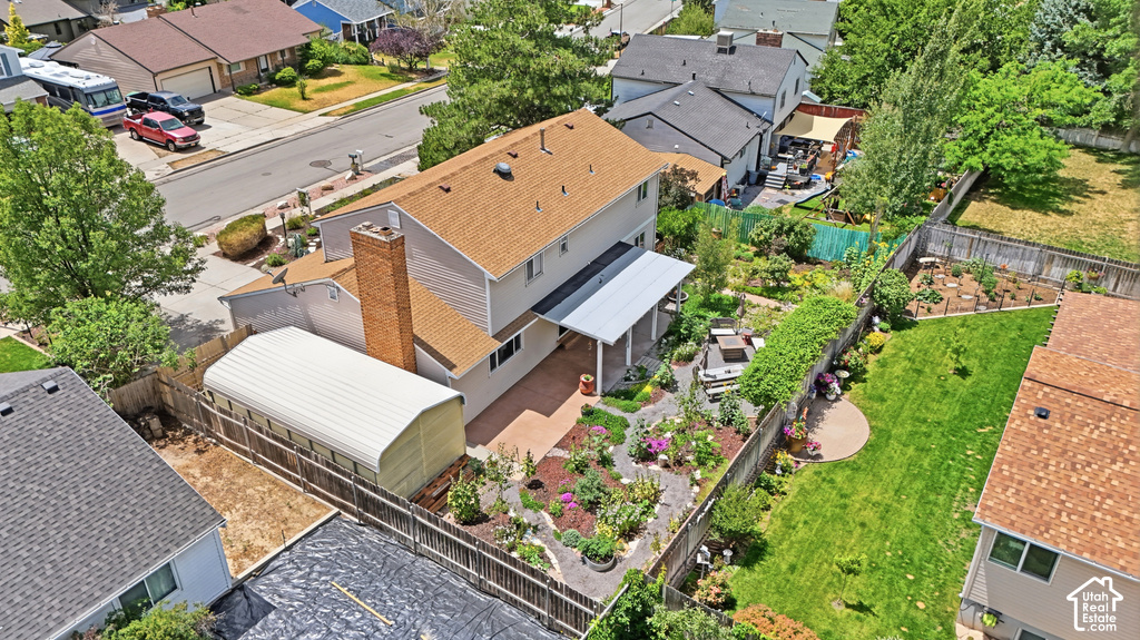 Expansive backyard featuring a manicured lawn, established garden beds, and a patio with an overhead cover