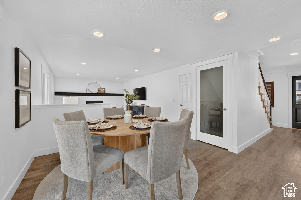 Dining area with wood-finish flooring, recessed lighting, and a white interior door with frosted glass panel