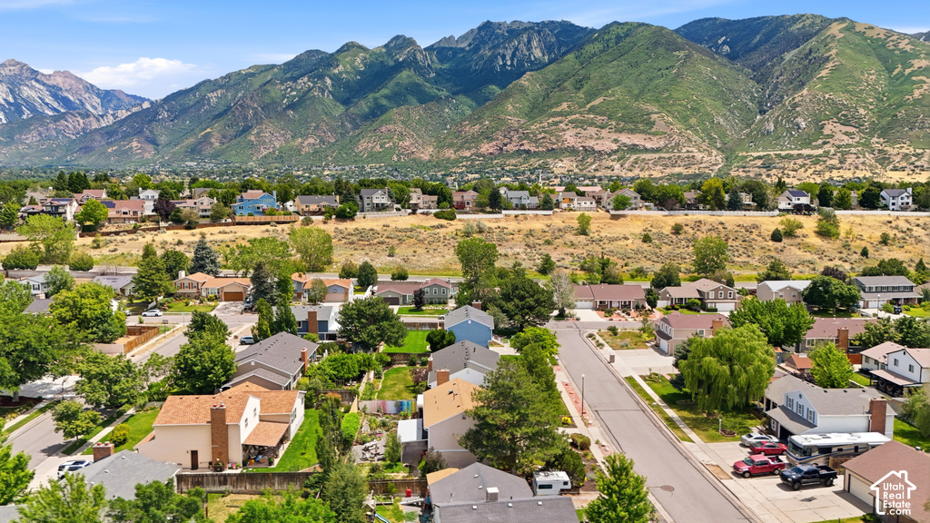 Expansive residential community featuring a variety of home styles, mature landscaping, and paved streets, all set against a dramatic mountainous backdrop