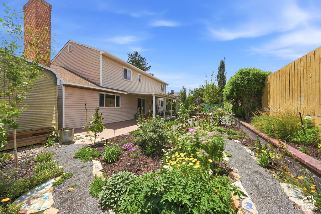 Expansive backyard featuring a gravel pathway, raised garden beds with mature plantings, and a private wood fence