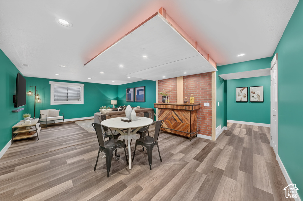 Spacious recreation area featuring wood-finish flooring, recessed lighting, and a built-in bar with a brick accent wall
