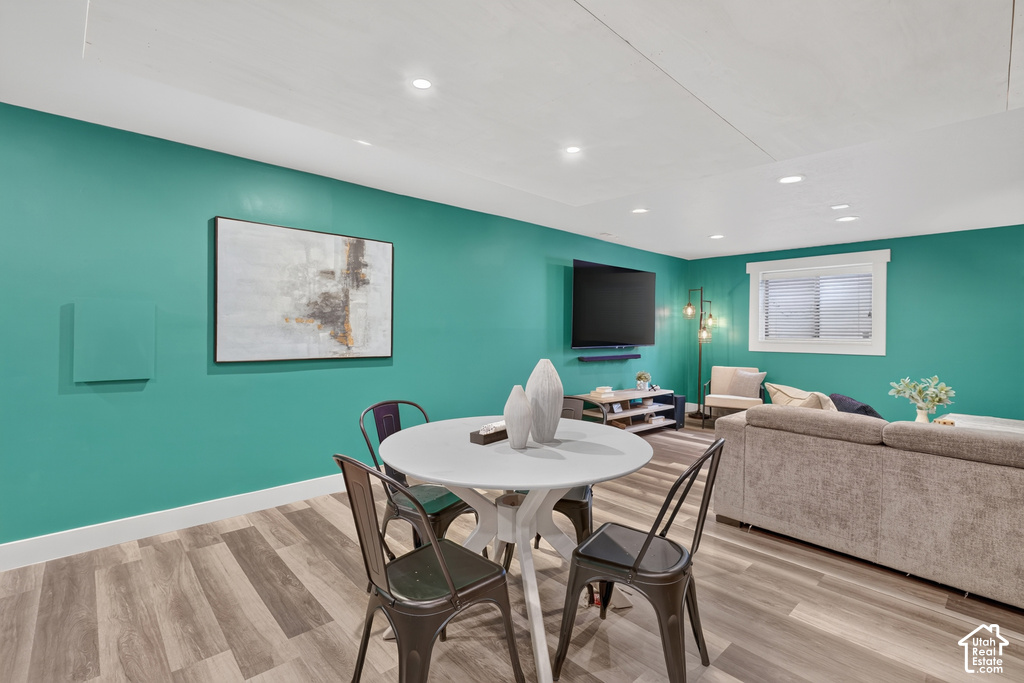Open-concept living space with wood-finish flooring, recessed lighting, and a white trim window