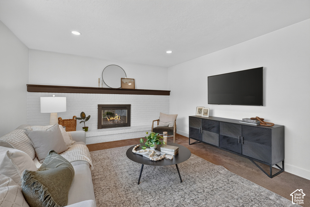 Living area featuring a white brick fireplace with a dark wood mantel, recessed lighting, and wood-finish flooring
