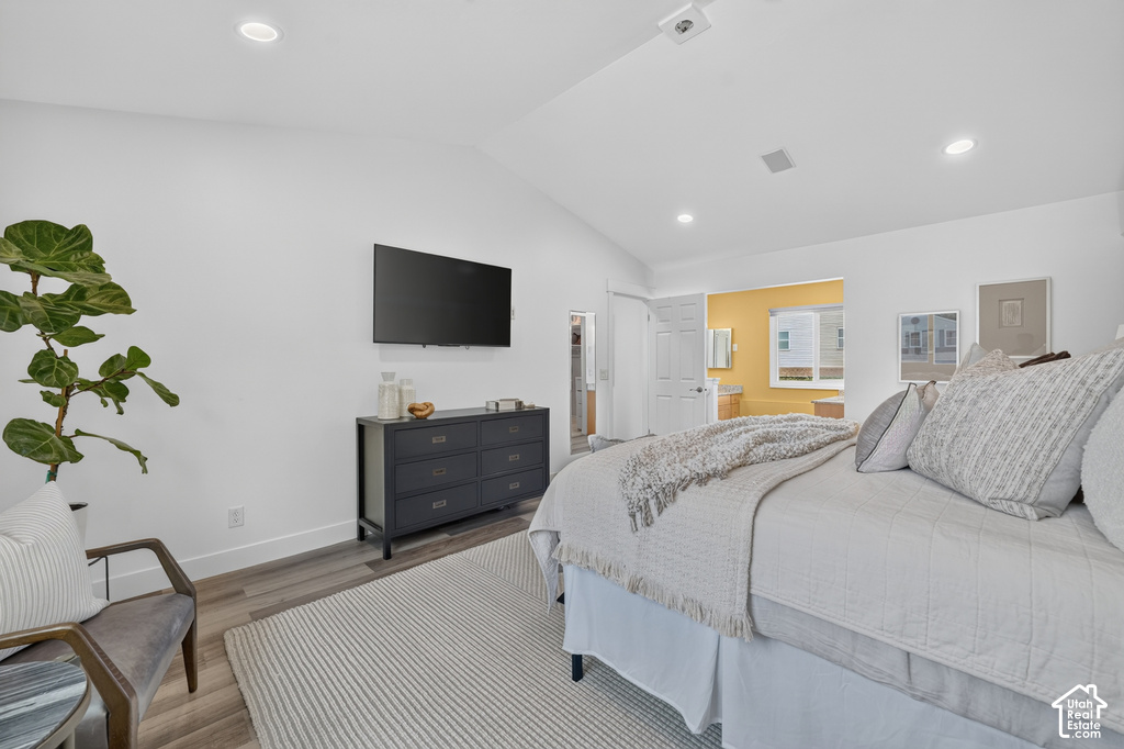 Vaulted ceiling bedroom featuring recessed lighting, wood-finish flooring, and a wall-mounted television