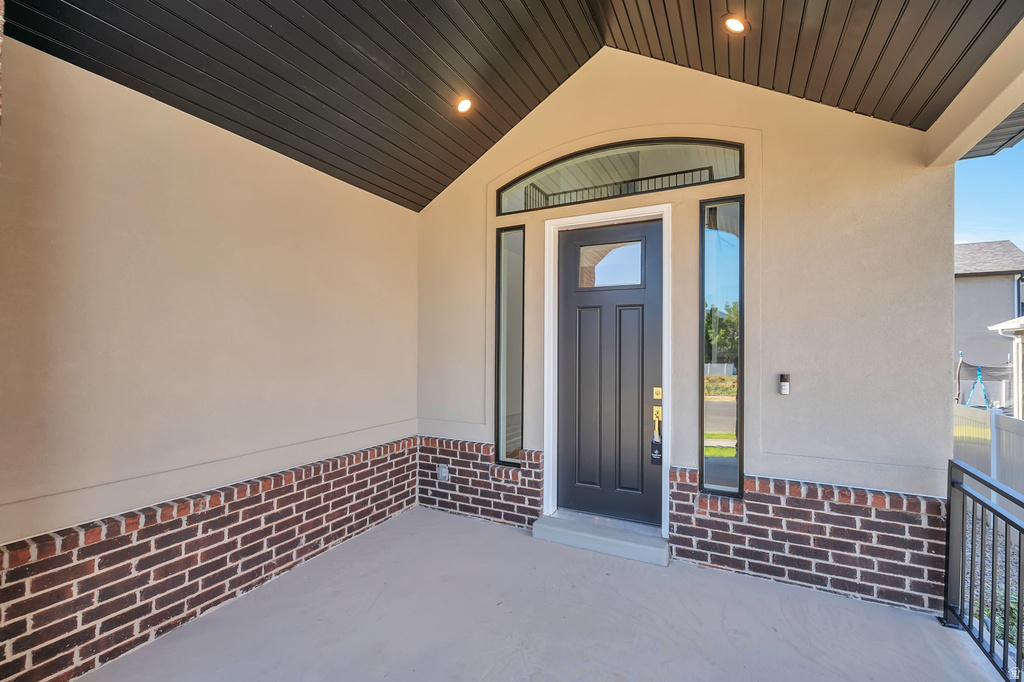 Covered entryway featuring a black paneled door with an arched transom window and sidelights
