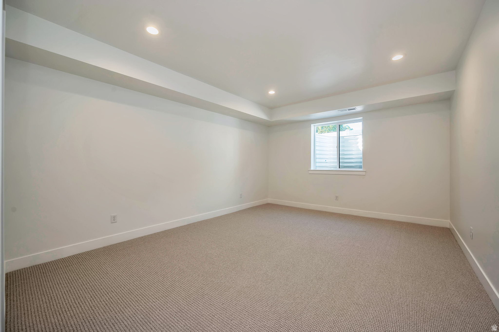 Spacious room with recessed lighting, light-toned carpeting, white walls, and a window featuring blinds and a window well