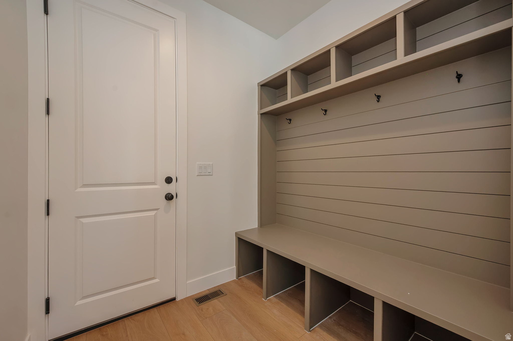Built-in mudroom storage featuring a bench, individual cubbies, upper shelving, and dark-finish coat hooks