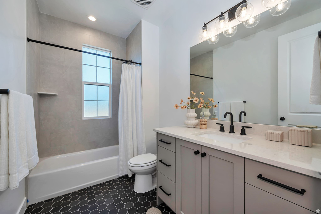 Bathroom featuring dark hexagonal floor tiles, a light gray vanity with a white countertop, and a recessed sink with matte black fixtures