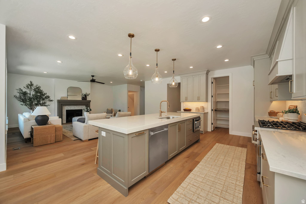 Open-concept kitchen featuring a large island with sink, stainless steel dishwasher, and pendant lighting