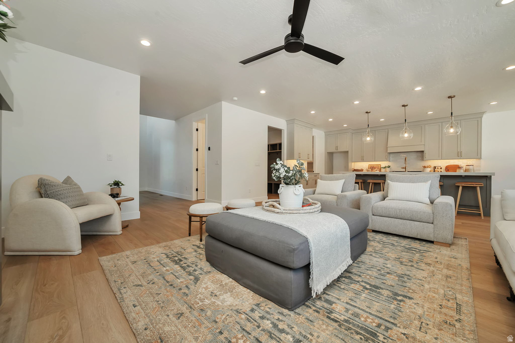 Open-concept living area featuring wood-finish flooring, recessed lighting, and a black ceiling fan