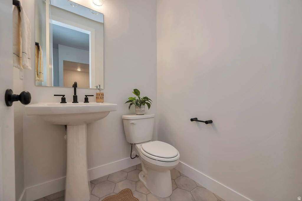 Pedestal sink featuring matte black fixtures, an illuminated mirror, and hexagon tile flooring