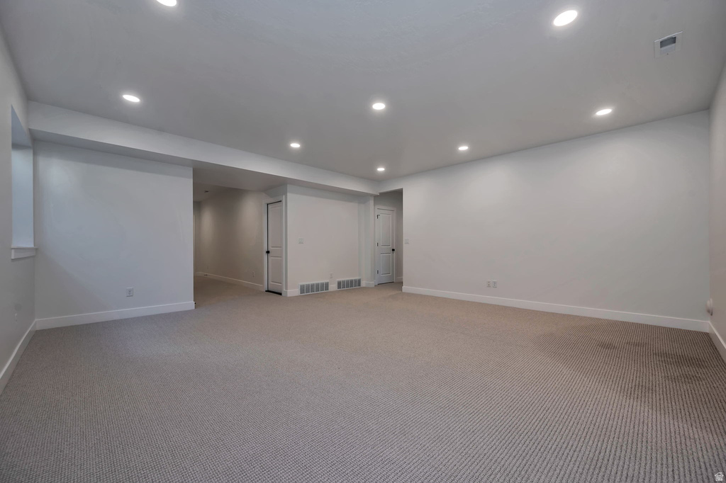 Expansive carpeted room featuring recessed lighting, a window, and two white paneled doors