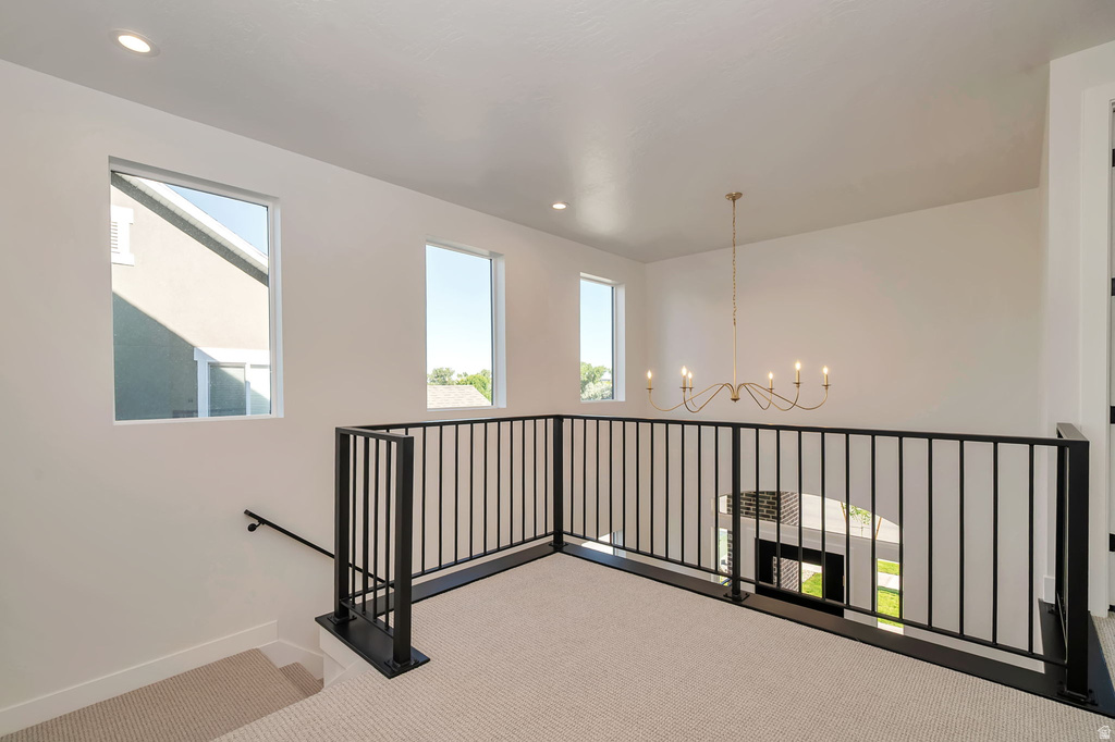 Upper-level landing featuring a metal spindle railing, light neutral carpeting, and multiple windows