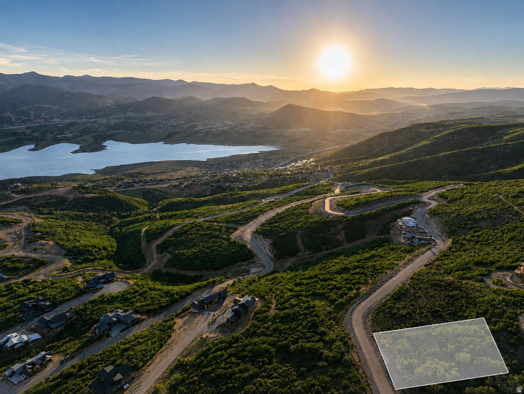 Elevated building lot featuring a natural, verdant landscape with a prominent lake and mountainous terrain in the background