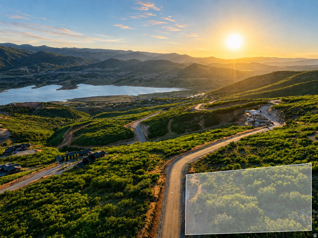 Expansive mountain landscape featuring a large lake, winding paved roads, and multiple residential structures