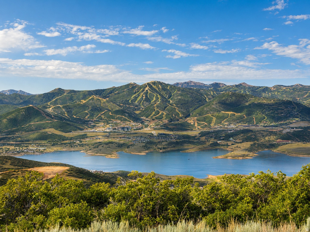 Expansive mountain landscape featuring a large body of water, distant structures, and ski slopes