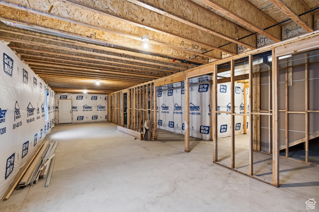 Unfinished basement with concrete flooring and exposed wood ceiling joists