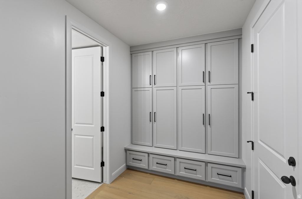 Built-in storage cabinetry with a light gray finish, black hardware, and integrated bench seating