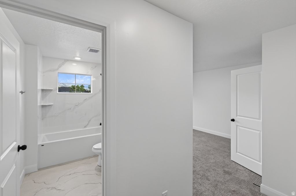 Full bathroom featuring a window above the tub, built-in shelving, white tiled flooring, and a white tub with white tiled surround