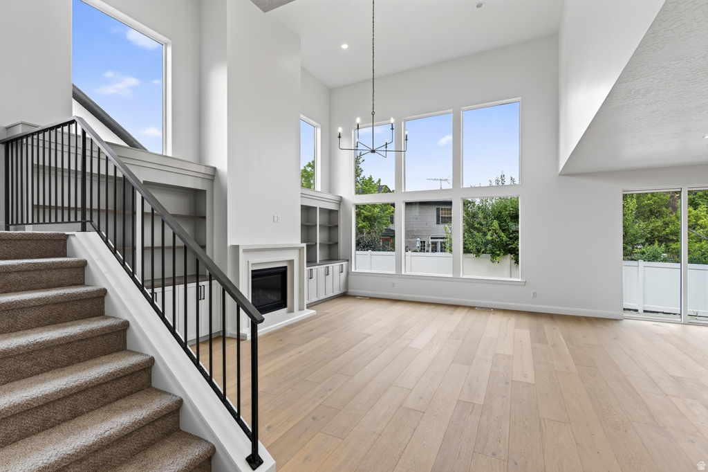 Spacious interior featuring a carpeted staircase with black iron railing, wood-finish flooring, a contemporary fireplace with mantel, built-in shelving, and large windows