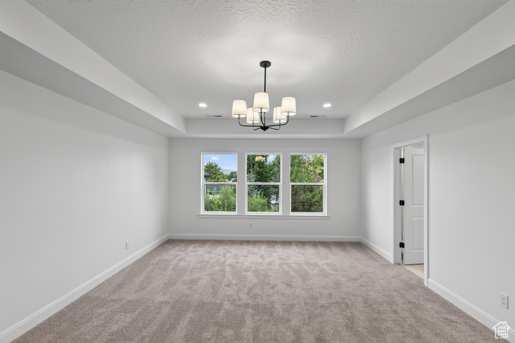 Spacious room with a tray ceiling, recessed lighting, and a contemporary chandelier