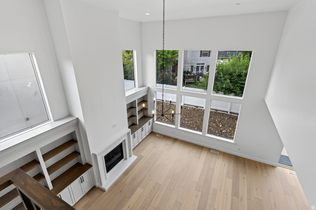 Two-story living area featuring a prominent fireplace, extensive built-in cabinetry with wood-finish shelving, and light wood-finish flooring