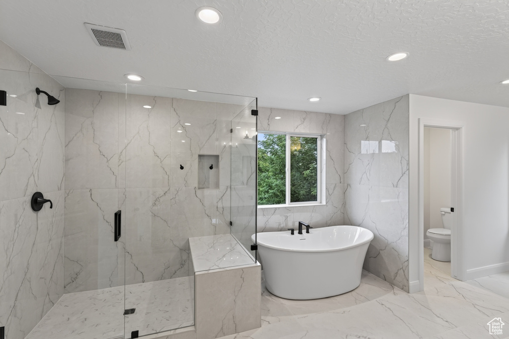 Spacious bathroom featuring a freestanding soaking tub with matte black fixtures, a walk-in shower with a built-in bench and matte black hardware, and large format marble-look tile flooring and walls