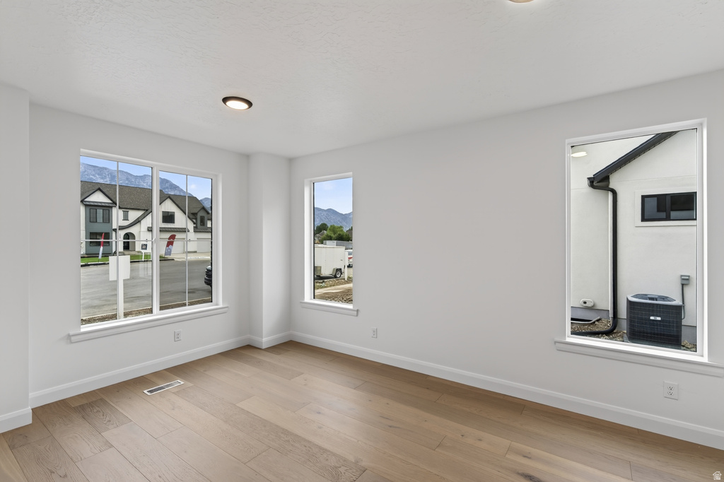 Bright interior space featuring light wood-finish flooring, recessed ceiling lighting, and multiple windows with white trim