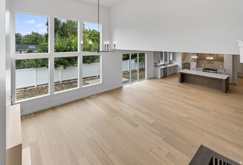 Open-concept living space featuring high ceilings, light wood-finish flooring, and a contemporary chandelier