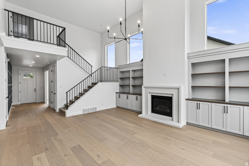 Open-concept living space featuring wood-finish flooring, a contemporary fireplace with a white mantel, and built-in shelving with lower cabinetry