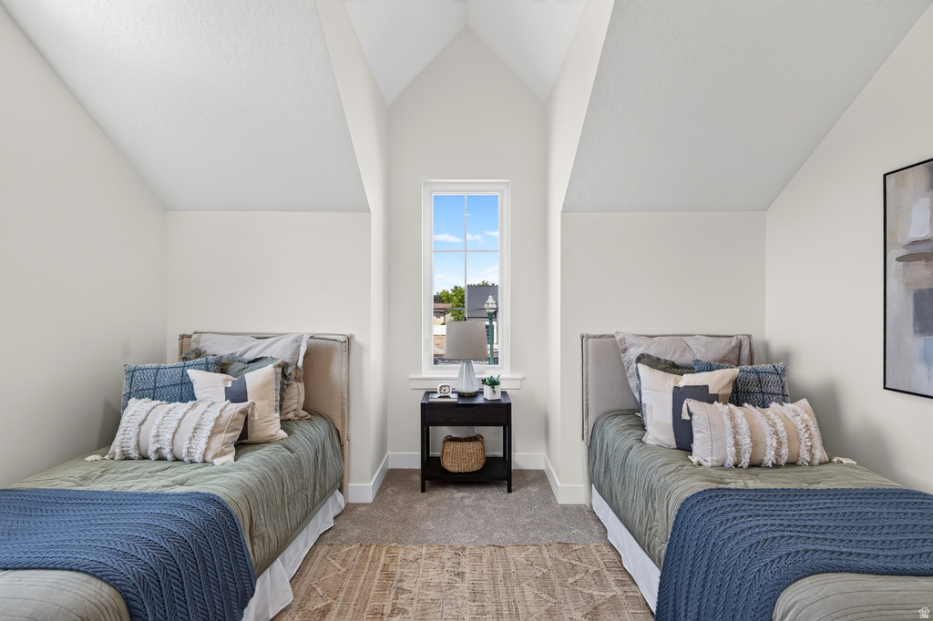 Vaulted ceiling bedroom featuring a central window, carpeted flooring, and white baseboards