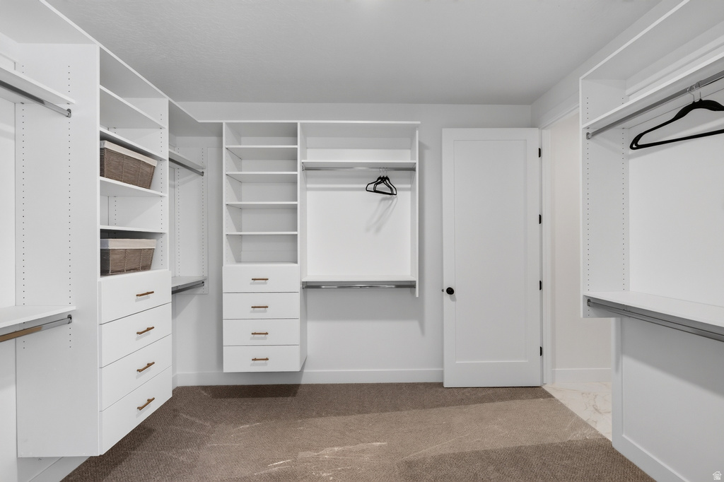 Custom closet system featuring white built-in shelving, multiple hanging rods, and integrated drawers with bronze-finish hardware