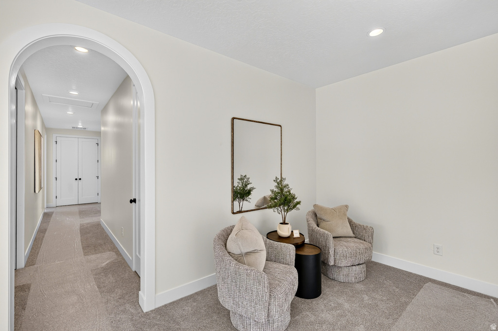 Archway entry to a hallway with recessed lighting, light neutral wall paint, and white baseboards
