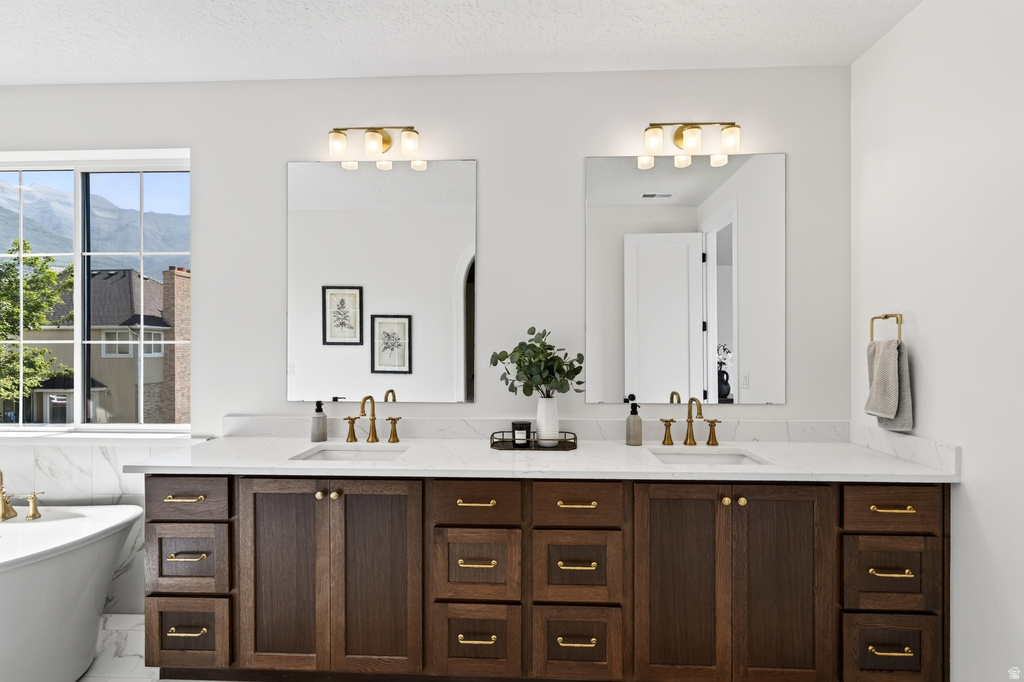 Double vanity with wood-finish cabinetry and brass hardware, featuring white countertops and undermount sinks