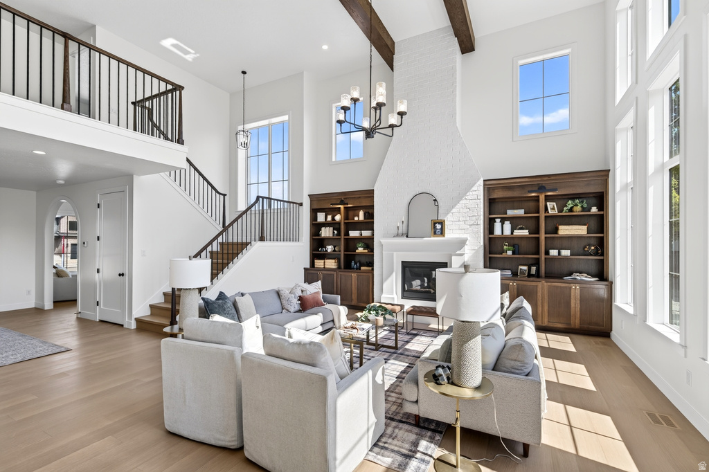 Two-story living area featuring a prominent fireplace with a white brick surround, built-in dark wood shelving, and wood-finish flooring
