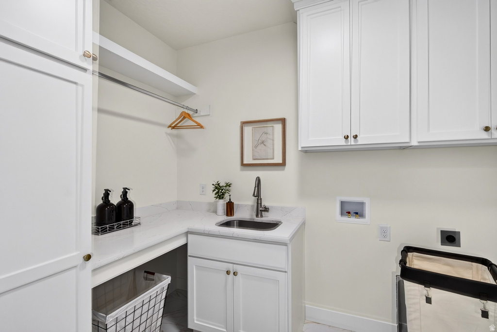 Laundry area featuring a built-in sink, white cabinetry, a floating shelf with hanging rod, and light-toned countertops