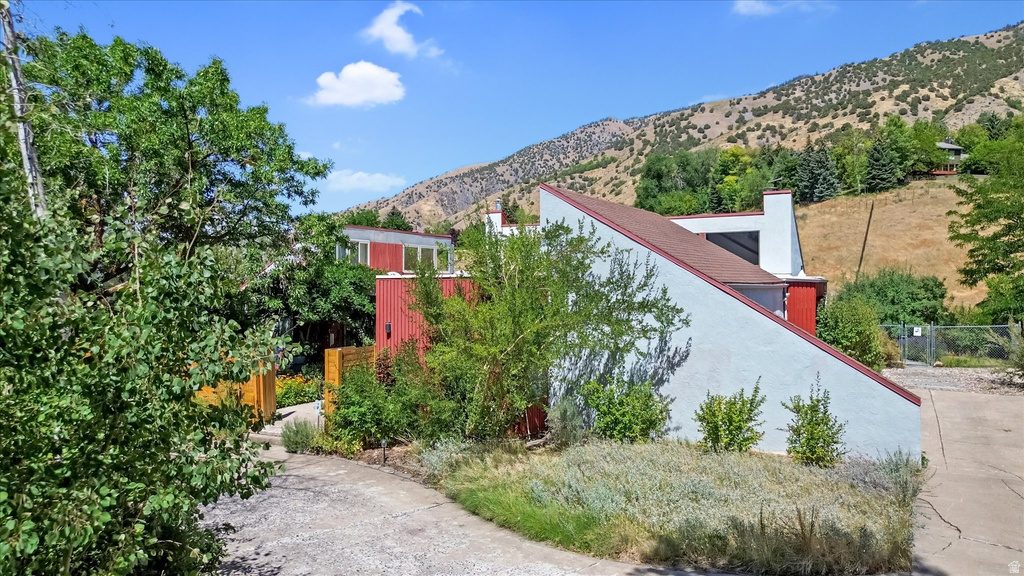 Modern architectural design featuring a red and white exterior, a sloped roofline, a visible chimney, and mature landscaping