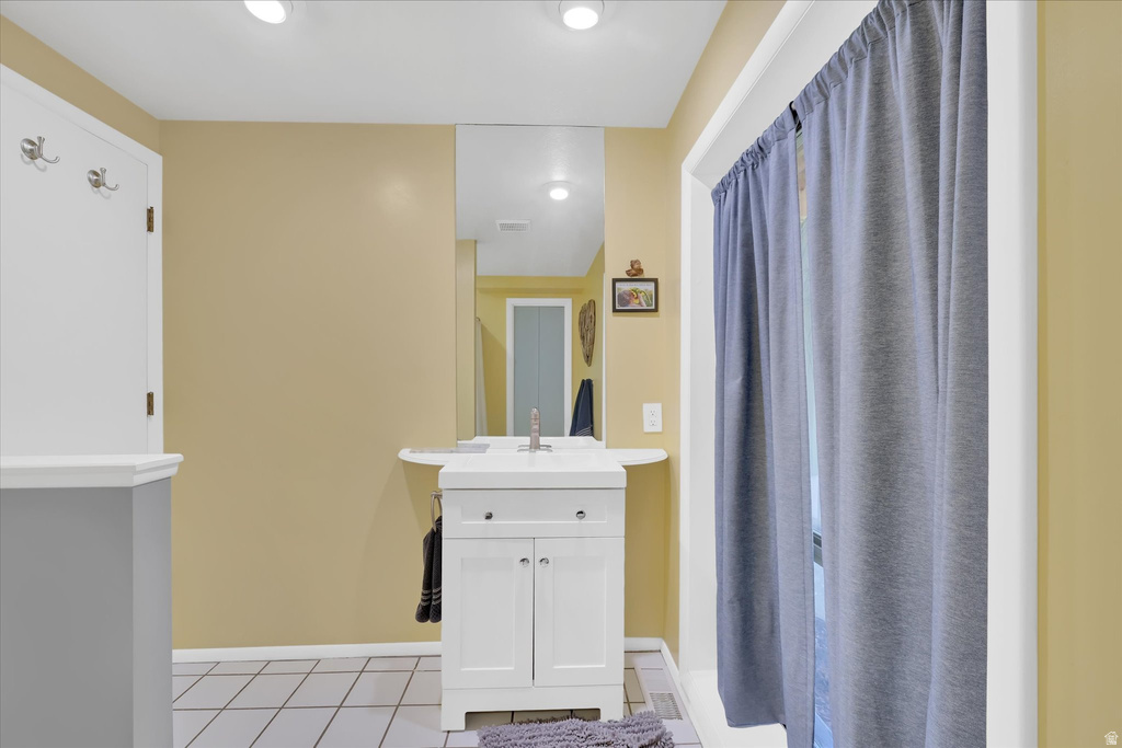 Bathroom featuring a white vanity with integrated sink, chrome faucet, and mirrored wall