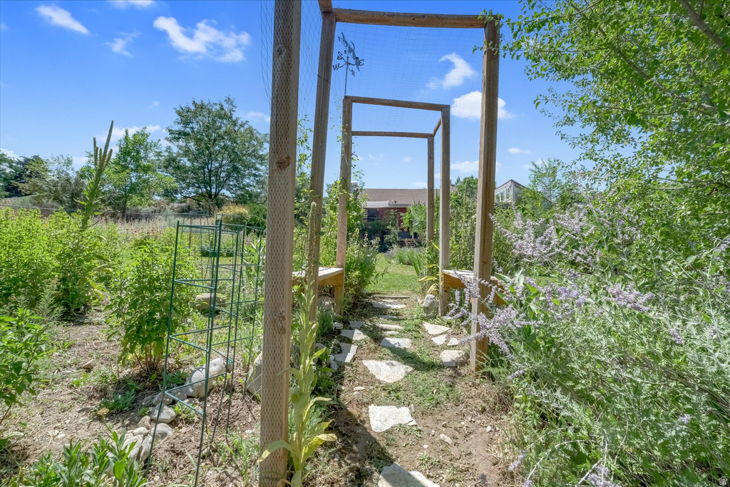 Landscaped garden path featuring stone pavers, natural wood arbor, and established perennial plantings